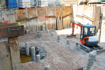 New building under construction. Excavator and bulldozer near the old house.