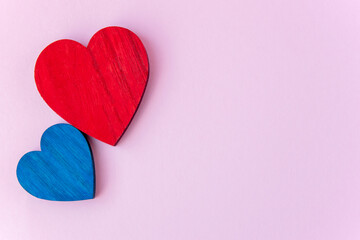 Blue and red wood hearts on the pink background with space for text.