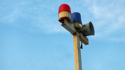 Fototapeta premium Marine signal light and emergency signal lamp off during the day with blue sky background. Navigation lamp of vessel on rusted iron. Red and blue of marine lamp or warning signal on vessel or boat.