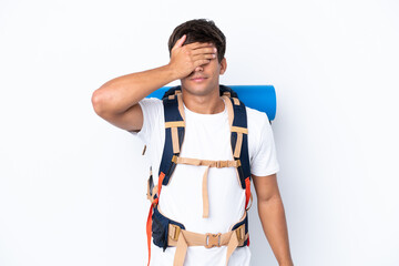 Young mountaineer woman with a big backpack over isolated white background covering eyes by hands....