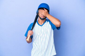 Baseball caucasian man player with helmet and bat isolated on blue background covering eyes by...