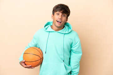 Handsome young basketball player man isolated on ocher background with surprise facial expression