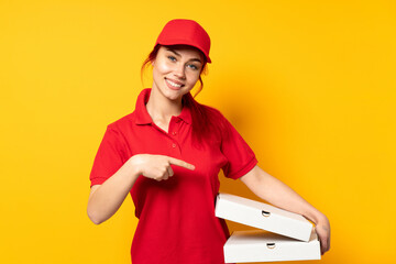 Pizza delivery girl holding a pizza over isolated background holding copyspace imaginary on the...