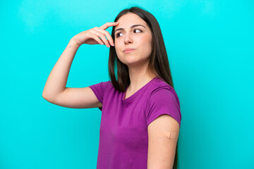 Young girl with band-aids isolated on blue background having doubts and with confuse face expression