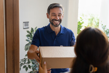 Female client accepts package box handed over by friendly deliveryman professional, representing...