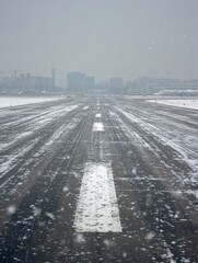 Obraz premium Snow Covers the Runway at a Bustling Airport During a Winter Storm While Flights Face Delays and Cancellations