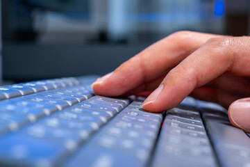 Close-up of hands typing on a backlit keyboard at a modern office desk, dual monitors glowing with code and data visuals. Ideal for tech ads, digital workspace, and software development campaigns.