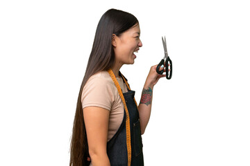 Young Asian seamstress woman over isolated background laughing in lateral position