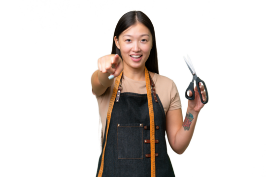 Young Asian seamstress woman over isolated background surprised and pointing front