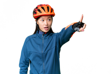 Young cyclist woman over isolated chroma key background pointing away