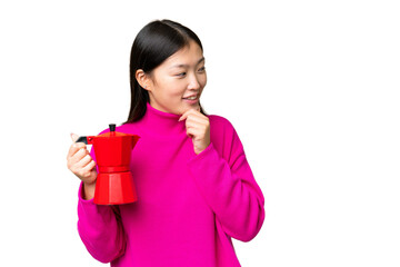Young Asian woman holding coffee pot over isolated chroma key background thinking an idea and...