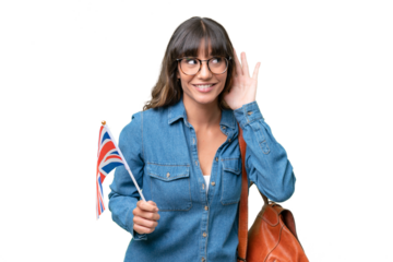 Young caucasian woman holding an United Kingdom flag over isolated background listening to something by putting hand on the ear
