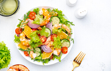 Fresh seafood salad with big juicy shrimp orange, lettuce, tomatoes, cucumbers, onion and white sesame with olive oil, top view