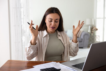 Woman sits at desk surrounded by bills and financial documents, feels stressed due to mistake in...