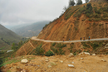 Group of foreign tourist walking together along cliffside dirt road in Sapa, Vietnam. 