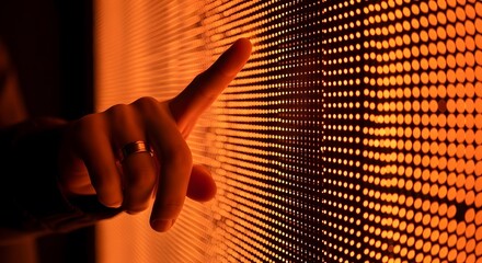 A hand with a pointed index finger touches an illuminated wall of small, closely spaced dots, creating a sense of interaction and technology.