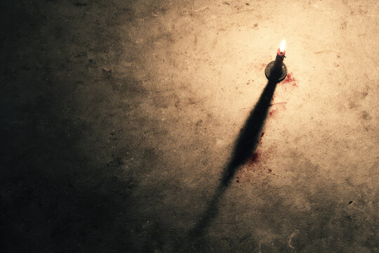 Candle flame shadow suspenseful crime poster tipped casting dramatic dark atmosphere. single candle with long shadow on textured surface creates suspenseful dramatic crime scene mood