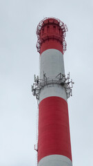 Red and white industrial chimney reaching for cloudy sky