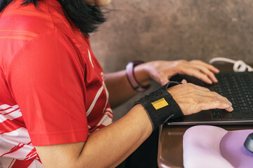 Hands of woman with thumb spica finger splint using computer mouse  to work. Woman work on desk...
