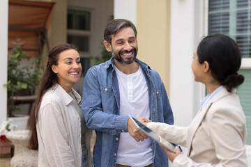 Pretty Latin couple greets real estate agent, start property transaction meeting stand outdoors on...