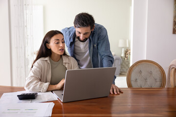 Couple managing household finances, reviewing digital statements, or calculating expenses, paying bills through electronic bank using modern laptop. Tracking spending or planning upcoming payments