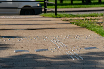 Tactile paving with textured surface patterns on pedestrian sidewalk for visually impaired accessibility, safety guidance system at urban crosswalk for inclusive city infrastructure