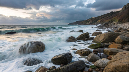 Obraz premium Rocky coastline with waves crashing over boulders during stormy weather creating dramatic seascape with moody cloudy sky overhead.