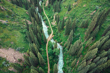 Aerial view of a winding turquoise river flowing through a lush green valley and dense coniferous...