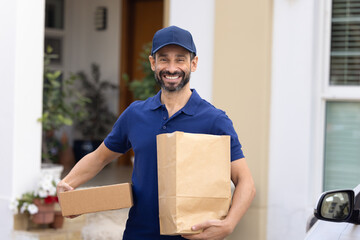 Portrait of courier brings to client house bag with foodstuff from market or restaurant and parcel...