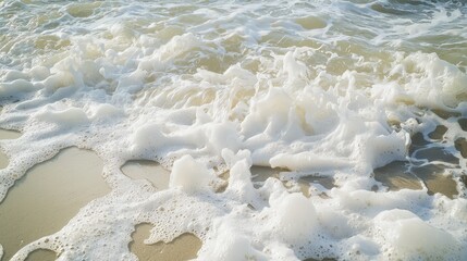 Clear sea water with white foam at the sandy beach