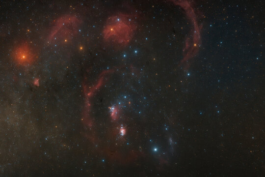 Deep space astrophotography of an emission nebula with vivid red hydrogen-alpha clouds, scattered blue stars, and intricate dark dust lanes, captured in high detail.