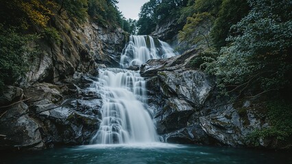 Fototapeta premium An impressive long exposure image showcasing the smooth, flowing waters of a majestic waterfall surrounded by rugged peaks.