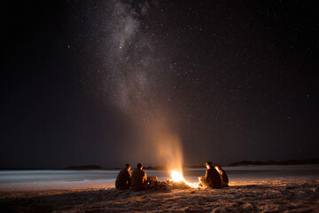 Friends gathered around a beach bonfire under a breathtaking Milky Way. Evokes connection, adventure, and tranquility. Perfect for travel, lifestyle, or inspirational content.