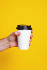 Hand holding a blank hot coffee mug, a paper cup, or a stainless steel thermos container