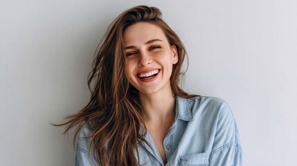 Naklejka premium Cheerful young woman expressing joy against a neutral background while wearing a casual button-up shirt