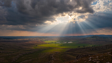 Majestic rays of sunlight break through clouds over lush valley