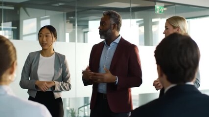 A diverse group of business professionals gathers in a modern setting, engaging in a collaborative discussion with focused attention.