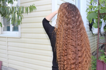 young girl helps her long and beautiful hair
