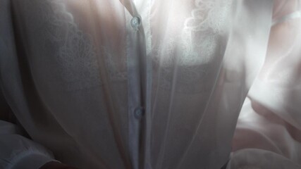 Woman buttoning blouse, sheer white shirt, lace bra, soft natural light, morning routine