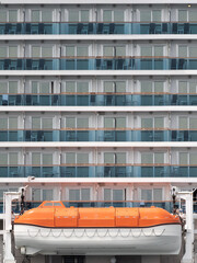 Lifeboat against rows of passenger cabins on big cruise ship at day