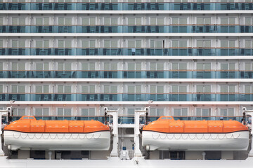 Lifeboat against rows of passenger cabins on big cruise ship at day