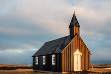 Búðir black church in Iceland, illuminated by the warm light of sunset. A peaceful and iconic...