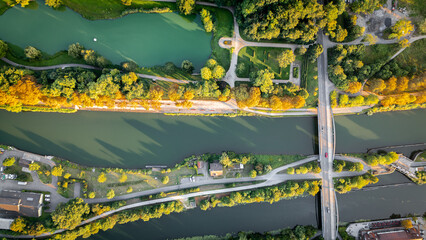 Aerial top-down view of a bridge crossing over a canal, with roads, pathways, and lush green trees...