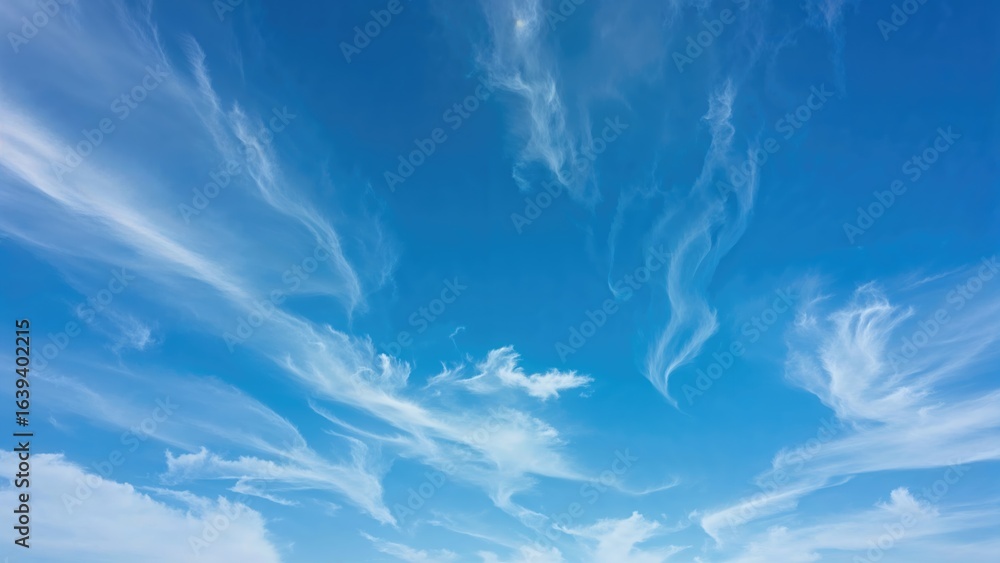 Poster time-lapse view of white clouds gliding through multiple layers in a sunny blue sky.