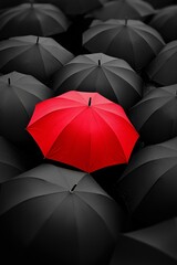 Bright red umbrella standing out among a group of black umbrellas, symbolizing individuality and uniqueness