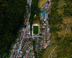 Aerial top-down view of a small town with a central sports field, surrounded by houses, roads,...