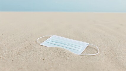 Protective face mask lying on a sandy shore