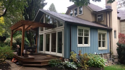 Fototapeta premium Cozy suburban home exterior with wooden decking and large glass windows surrounded by lush greenery in a tranquil backyard setting