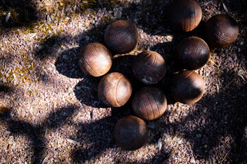 Rustic bocce balls on gravel path in sunlit shadow