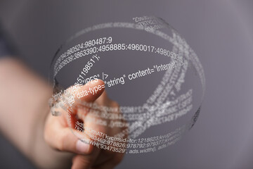 A hand interacts with a futuristic, transparent hologram displaying lines of code, representing digital technology and innovation.